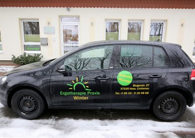 Praxiseigener PKW mit Aufschrift vor der Praxis