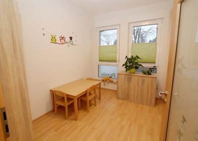 Kinder-Behandlungsraum mit Tisch, Stühlen und kleinem Schrank