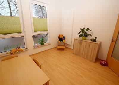 Kinder-Behandlungsraum mit Tisch, Kinderstuhl mit Puppe und kleinem Schrank