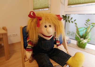 große Puppe auf Kinderstuhl